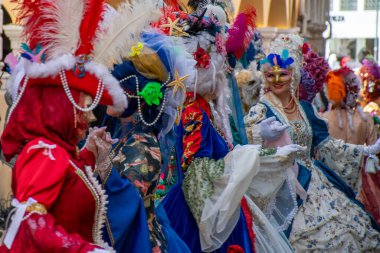 Şenlikli bir etkinlikte maskeler, tüyler ve zarif, renkli tasarımlarla süslenmiş kostümler..