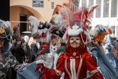 Şenlikli kostümler ve maskeler içindeki insanlar karnavalı ayrıntılı başlıklar ve süslü giysilerle kutluyorlar..