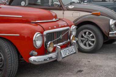Korfu, korfu, Yunanistan. 16 Şubat 2025: Kırmızı Volvo Amazon ve kahverengi Volkswagen Böceği yan yana park etti.