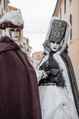 Venedikli maskeli çift geleneksel giysiler içinde, zamansız gizem ve güzelliği yakalıyorlar..