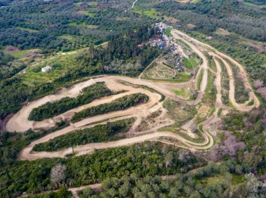 Toprak bir pistin havadan görünüşü yeşil bir arazide dönüyor, eğriler ve sıçramalar gösteriyor..