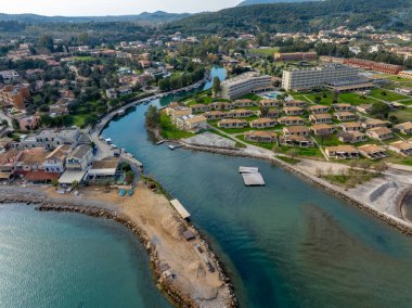 Otelleri ve yemyeşil yeşillikleri olan sakin bir nehrin kıyı kasabasından geçişi..