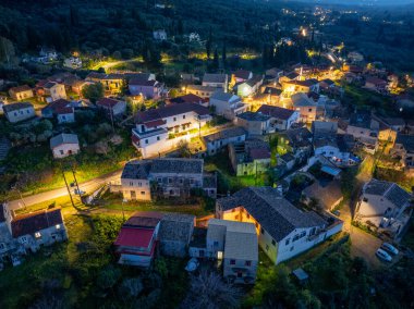 Karanlık çöktüğünde bir köyün havadan görünüşü karanlık bir ormanın arka planına karşı aydınlatılmış tuhaf evleri yakalıyor..