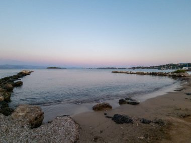 Sakin bir sahil manzarası sakin bir körfez, kumlu bir sahil ve alacakaranlıkta sakin bir atmosfer gösteriyor..