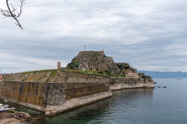 Tarihi bir taş kale, bulutlu bir gökyüzünün altında okyanus sularıyla çevrili küçük bir adada nöbet tutuyor..