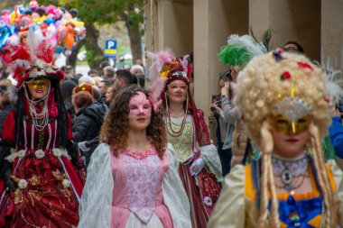 Maskeli insanlar sokaklarda şenlikli bir kutlama için geçit töreni yapıyorlar..