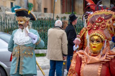 Canlı giyinmiş, özenle hazırlanmış kostümler ve maskeler giymiş insanlar sokakta karnavalı kutluyor..