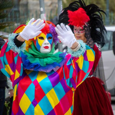 Karmaşık kostümler ve maskeler içindeki insanlar renkli bir sokak karnavalı kutlamasına katılıyorlar..