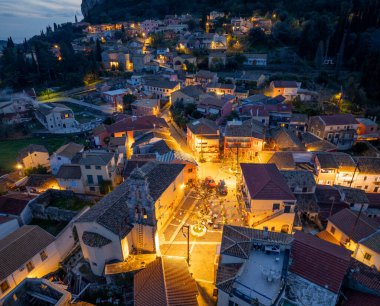 Alacakaranlıktaki bir köyün havadan görünüşü. Bina ışıkları sokakları ve taş binaları aydınlatıyor..
