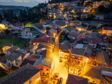 Yamaçta yuva yapmış, sıcak ışıklarla aydınlatılmış büyüleyici bir Avrupa köyünün akşam manzarası..
