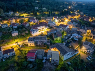 Büyüleyici bir hava görüntüsü seramikli çatıları ve aydınlık pencereleri olan büyüleyici bir köyü gözler önüne seriyor. Alacakaranlık gökyüzünün altında yeşil bir araziye yerleştirilmiş..