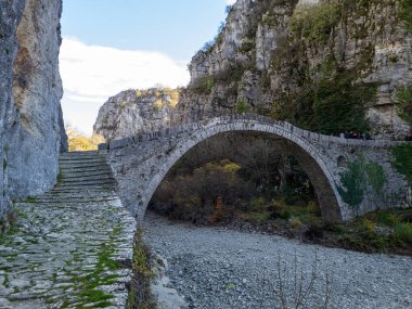 Taş köprü, kayalıkları birbirine bağlayan kurumuş bir nehir yatağını geçer. Yeşil ve ağaçlar temiz bir gökyüzünün altındaki tarihi taş yapıyı çevrelediler..
