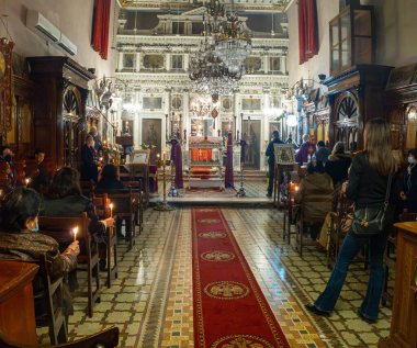İnsanlar klasik bir kilisede dini bir ayine katılıyorlar. Tapınak içinde dua ederken ellerinde mumlar tutuyorlar.. 