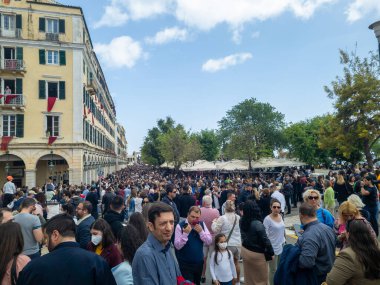 Bir şehir caddesinde büyük bir insan kalabalığı duruyor. Eski Avrupa mimarisi, güneşli bir günde yol boyunca ağaçlarla kaplı..