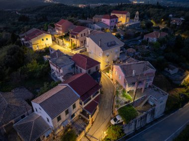 Alacakaranlıktaki büyüleyici bir köyün hava manzarası, manzaranın her tarafına renkli evler saçılmış, yumuşak sokak lambalarıyla aydınlatılmış.. 