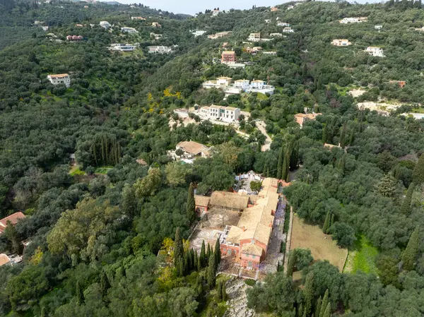 Yoğun ormanlaşma ve dağınık konutlarla çevrili kırmızı çatı binaları olan bir yamaçta gözlerden uzak bir arazi. Verdant Valley, güneşli gökyüzü.