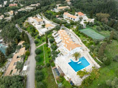 Korfu, korfu, Yunanistan. 15 Mart 2025: Yunanistan 'da bir yüzme havuzu, tenis kortu ve yemyeşil yemyeşil bir tatil beldesinin havadan görünüşü.