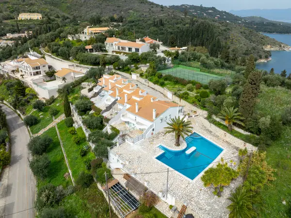 Korfu, korfu, Yunanistan. 15 Mart 2025: Yunanistan 'da lüks bir villa kompleksinin havadan görünüşü, yüzme havuzu, tenis kortu ve yemyeşil peyzaj.