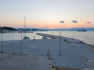 Korfu, korfu, Yunanistan. 15 Ağustos 2020: Tekneleri ve uzak tepeleri olan bir Yunan limanında gün batımı.