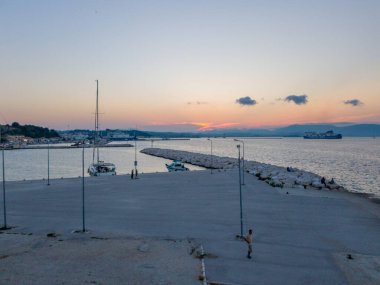 Korfu, korfu, Yunanistan. 15 Ağustos 2020: Yelkenli, feribotlu ve akşamdan keyif alan insanlarla birlikte bir Yunan limanında gün batımı.
