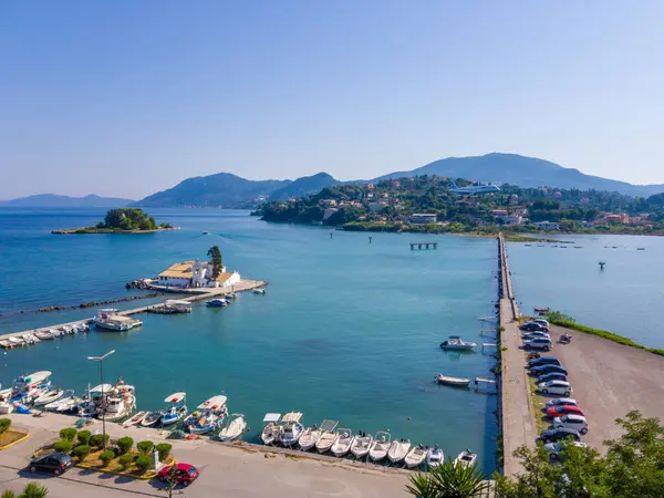 Dağlar ve kıyı evleri tarafından desteklenen bir yapıya sahip bir adaya uzanan turkuaz su üzerine uzanan uzun bir köprünün havadan görünüşü.