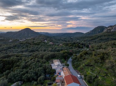 Gün batımında bir vadinin nefes kesici panoramik görüntüsü, doğanın güzelliğini, sakin bir okyanusu ve kırsal binaların kırsal cazibesini gözler önüne seriyor..
