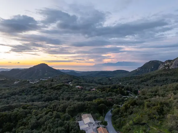 Nefes kesen bir manzara heybetli dağları yakalıyor dingin denizle buluşmak için iniyor, canlı bir günbatımı ve bulutlu bir gökyüzü ile taçlandırılıyor..