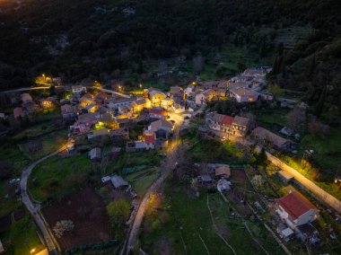 Bir köy yeşilliklerin arasında dinleniyor. Bir merkez yol geçidi sunarken, yapılar parıldıyor. Huzur ve doğa ile bağlantı uyuştur.