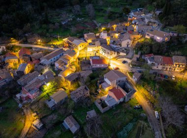 Yüksek açılı bir çekim, büyüleyici bir köyün samimi görüntüsünü yakalıyor. Altın ışıklar binalara sıcak bir ışık saçıyor..