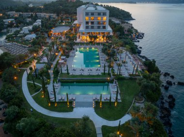 Havadan bakıldığında, çok sayıda havuz, geniş bahçeler, sahil yakınlığı ve deniz kenarındaki zarif gece aydınlatmasının yer aldığı sakin bir tatil beldesi görülüyor..