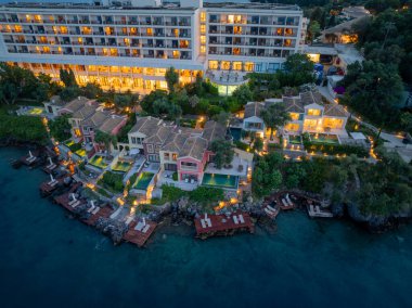 Havadan bakıldığında, sahilde villaları ve rıhtımı olan, alacakaranlık saatlerinde sıcak ışıkta yıkanan lüks bir tatil köyü görülüyor. Serene ayarı.