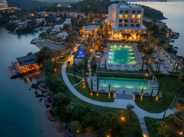 Göz kamaştırıcı bir hava çekimi, sakin bir ortamda parlak havuzlar, sahile giriş ve mimari dehayı vurgulayan bir tatil beldesini alacakaranlıkta sergiliyor..