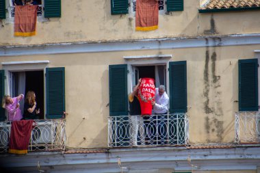 Balkonda elinde beyaz bir vazoyla duran iki kişi Avrupa 'daki apartman dairesinin balkonundaki şenliği kutluyorlar..