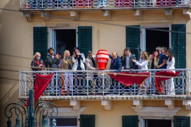 Bir grup geleneksel Paskalya geleneğinin bir parçası olarak balkondan büyük bir seramik demlik atmaya hazırlanıyor. Yeşil panjurlu bir bina arkaplan biçiminde.