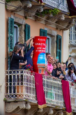 Korfu, korfu, Yunanistan. 23 Nisan 2022: Yunanistan 'ın Korfu şehrinde balkondaki insanlar, Ortodoks Paskalya kutlamaları sırasında Kutsal Cumartesi günü geleneksel esrar atma geleneğine katıldılar..