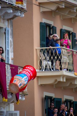 İnsanlar Yunanistan 'ın Korfu kentindeki balkonlarından büyük kırmızı bir nesnenin yukarıdaki balkondan düşüşünü kutluyorlar..