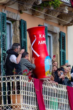 Heyecanlı bir grup insan, balkonda telefonlu büyük, kırmızı bir vazo yakalıyor ve mimari sahnelere heyecan katıyor.. 