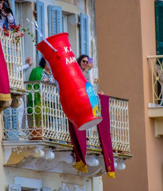 İnsanlar, binanın balkonundan kırmızı dekoratif bir çömlek fırlatılmasını içeren bir olayı gözlemleyerek geleneği simgeliyor. Kutlama ve şenlikler.