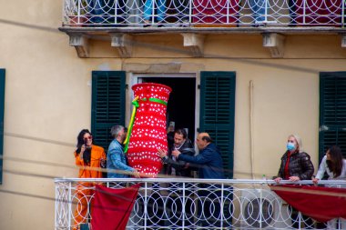 İnsanlar balkonda ellerinde büyük, süslü bir vazoyla bir araya gelip, açık hava şenliklerinde özel bir kutlama yapıyorlar..
