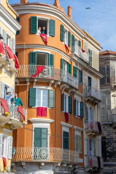 Kırmızı kumaşla dekore edilmiş balkonları ve pencereleri olan bir Avrupa binası..