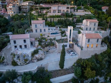 Korfu, korfu, Yunanistan. 20 Nisan 2025: Akşam karanlığında yamaçtaki bir köyde yenilenmiş taş evlerin havadan görünüşü.