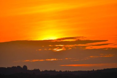 Altın saat siluetli manzarayı sıcak bir ışıltıyla yıkar, güneş ufkun altına batarken, gökyüzünü turuncu tonlarla boyarken..