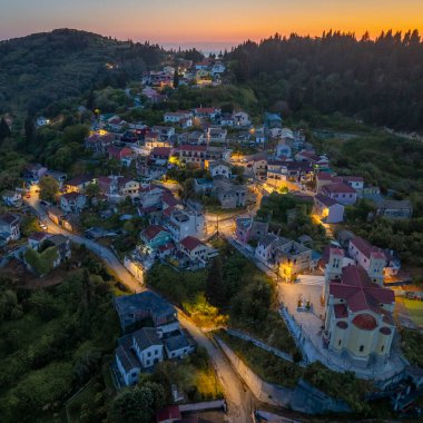 Alacakaranlıkta yeşil bir yamaçta kurulmuş büyüleyici bir köy geleneksel mimarisini sergiliyor ve batan güneşin sıcacık parıltısıyla banyo yapıyordu..