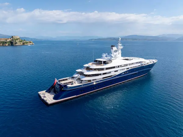 Ferah bir süper yat berrak mavi okyanus sularında süzülüyor, lüks bir rahatlama ve deniz macerası sahnesi sunuyor..