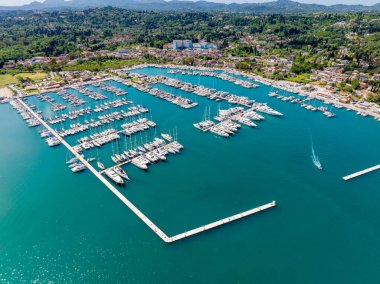 Havadan çekilen görüntülerde bir kasaba ve yeşil dağlarla çevrili sayısız yelkenli ve yatla dolu bir marina görülüyor.. 