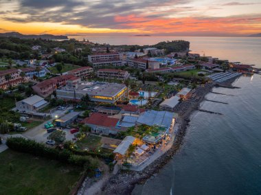 Renkli bir günbatımında okyanusun mimarisi ve sükunetini gösteren bir sahil kasabasının manzarası..