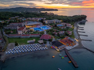 Alacakaranlıkta sahile kurulmuş lüks bir tatil köyü. Güzel plajlar, yüzme havuzları, kalacak yer ve gün batımının renkleriyle parlayan gökyüzü..