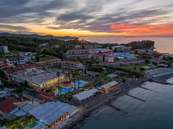 Bu manzaralı hava görüntülerinde, göletler, sahil, binalar ve huzurlu bir zemin sağlayan canlı bir günbatımı gökyüzü ile, alacakaranlıkta bir sahil tatil beldesi sergileniyor..