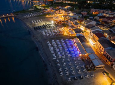 Geceleri, binaların yumuşak parıltıları, sıra sıra plaj sandalyeleri ve şehrin ışıklarını yansıtan okyanuslarla aydınlanan pitoresk bir sahil..