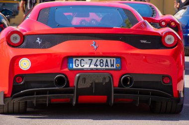 Modern kırmızı spor bir arabanın arkasına odaklanan yakın plan bir çekim. Plakası görünür, tasarım ve egzoz borularını vurguluyor..